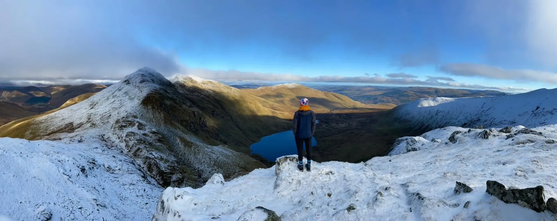 A hillwalker looking out over An Stuc and Lochan nan Cat from Ben Lawers in winter
